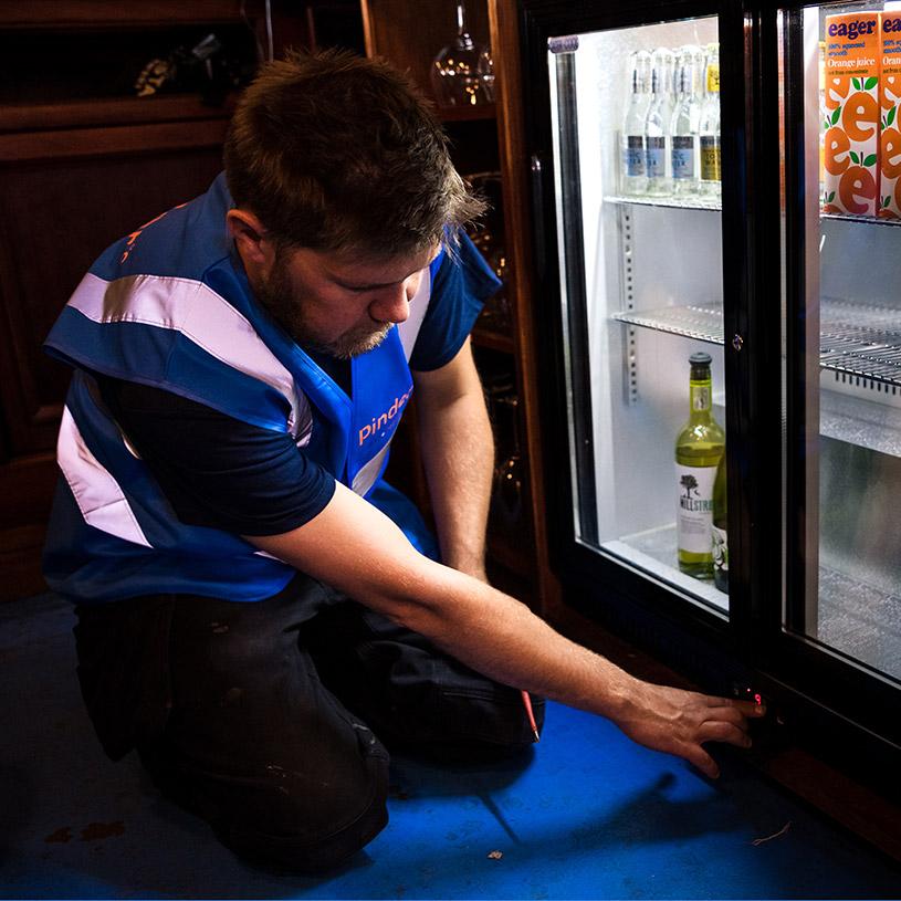 Pinder Cooling engineer maintaining a bottle fridge in a bar